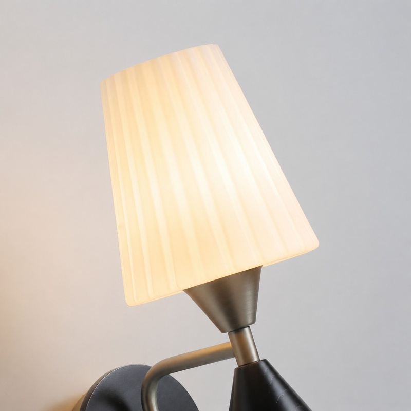 Glass shade and wall arm detail of matte nickel wall sconce