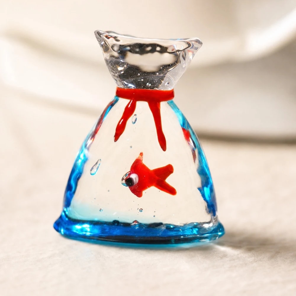 Triangular glass goldfish ornament on a tabletop