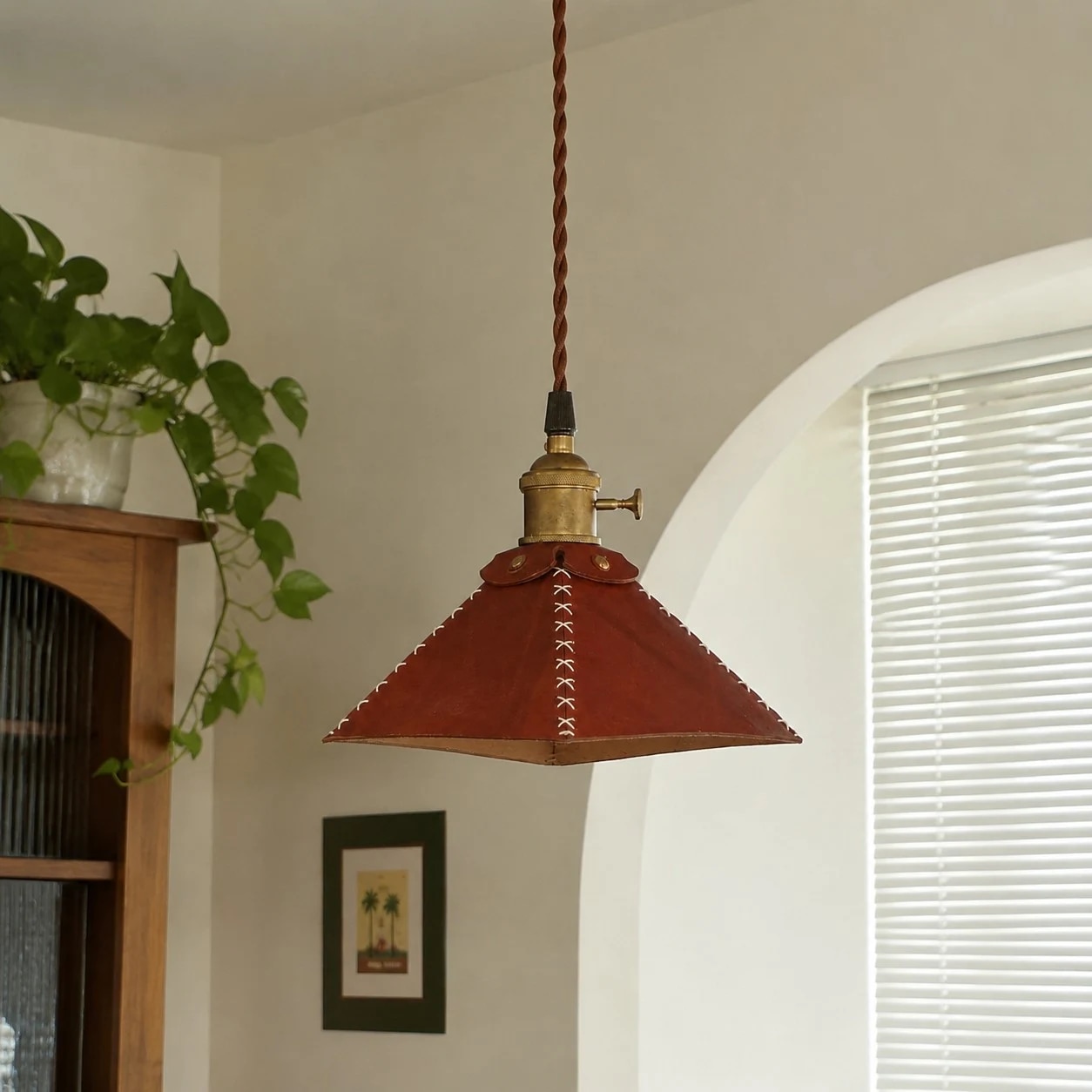Leather pyramid pendant lamp near a bright window and plants
