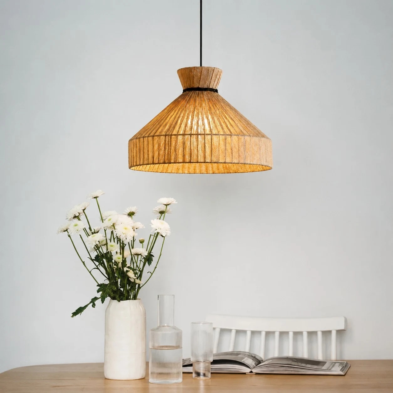 Fabric cone pendant light above a dining table with flowers