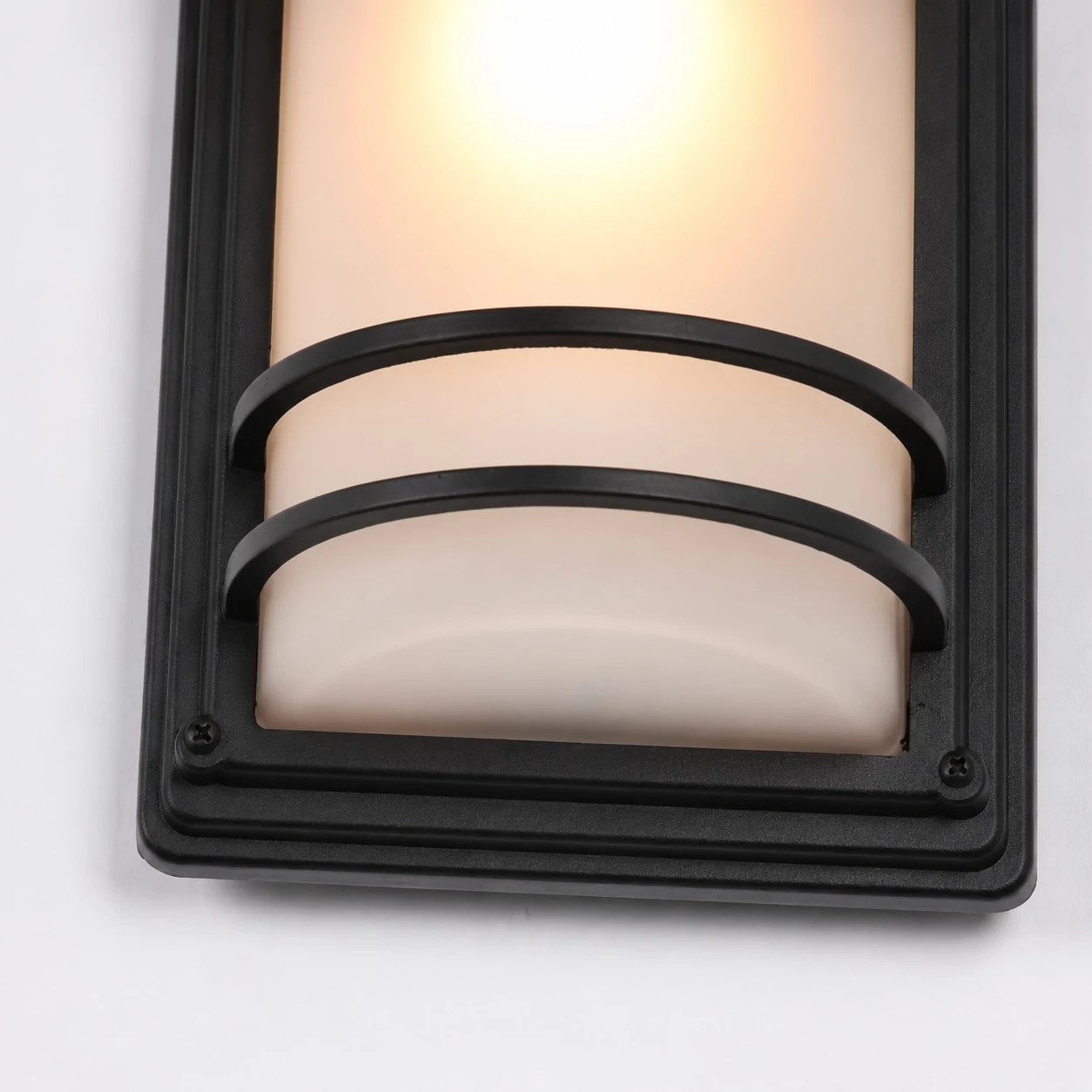 Close-up of glowing glass shade and black protective bars